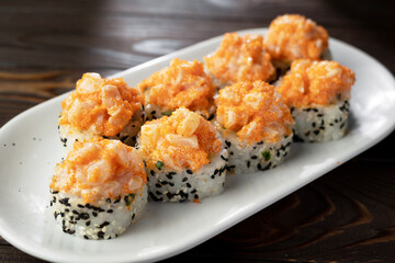 Top view of Japanese sushi volcano roll with white and black sesame. Served on plate. Dark wooden background