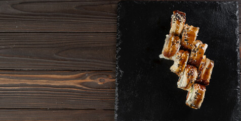 Sushi roll with salmon, smoked eel, avocado, philadelphia cheese on black background. Sushi menu. Japanese food concept.