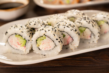 A set of fresh sushi rolls with crab surimi, avocado and black sesame seeds served on a plate. Japanese sushi uramaki or California roll. Sushi menu. Japanese food