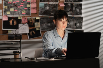 Detective processing evidence in her office using a laptop.