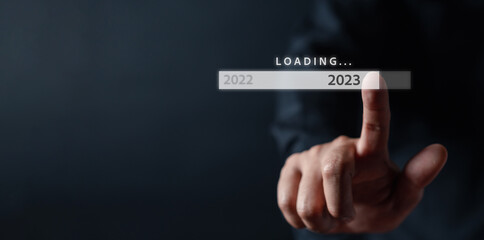 Businessman touching to virtual download bar and loading for New Year and changing year 2022 to 2023. start up planing business in next years concept...