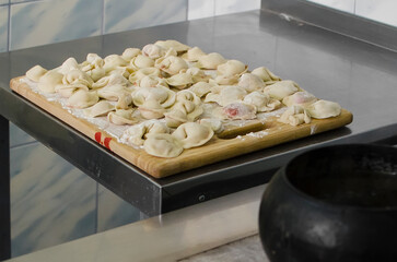 Process of making homemade raw pastry dumplings with meat filling on a wooden Board. Pelmeni. A traditional dish of Russian cuisine.