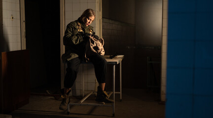 Post-apocalypse. a young woman sits takes out food supplies from a backpack in an abandoned building. concept of a man hiking in a post-apocalyptic world looking for food.