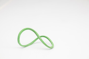 An abstract shaped green rubber band on a white background.