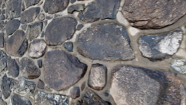 Stone wall made of large rocks and boulders - abstract background and texture of granite or marble retention wall.