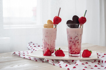 Sweet milk dessert on Valentine's Day. Delicious strawberry yogurt decorated with heart-shaped chocolate on a wooden table. Side view. Selective focus. Healthy breakfast.