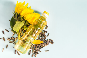 Sunflower oil in a transparent bottle sunflower seeds and sunflower flower close-up on a blue...