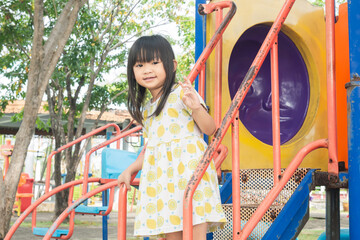 Portrait image of happy Asian child girl playing with slider bar toy at the park playground. 4-5...