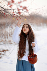 A girl on the street collects and plays with snow.