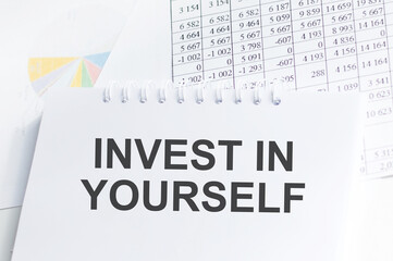 INVEST IN YOURSELF text on a paper on chart background
