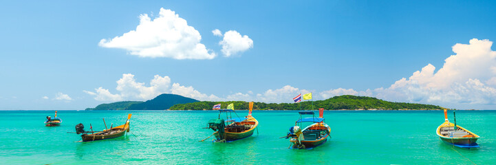 Boats in Rawai beach, Phuket, Thailand. Panoramic view of the beach of Rawai on the island, with traditional long tail fishing boats anchored on the beach.