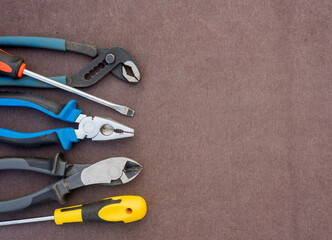 screwdriver pliers wire cutters in natural light on a brown desktop