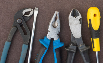 screwdriver pliers wire cutters in natural light on a brown desktop