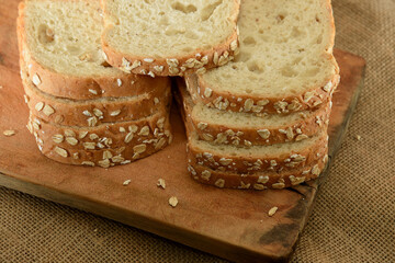 Piece of whole grain oat bread on a cutting board. White bread in the foreground, sliced ​​bread, nutritious.