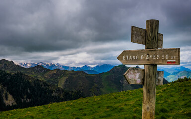 Trail indication signs with snowy mountains in the background near Ayes lake the French Pyrenees mountain range