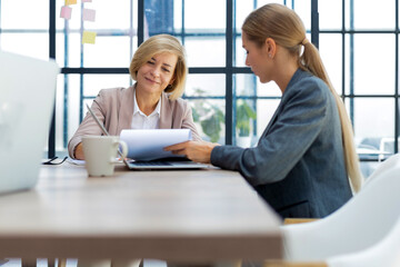 Image of two business women working in the office with documents.