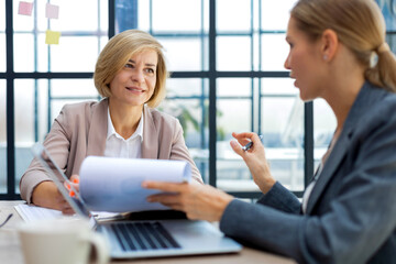 Image of two business women working in the office with documents.