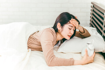 寝坊して目覚まし時計で起きる女性（遅刻）

