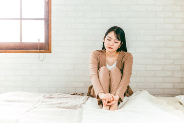 ベッドルームで憂鬱・退屈・トラブルで悩むパジャマ姿の日本人女性
