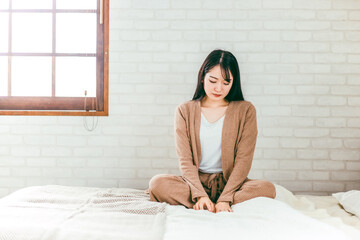 ベッドルームで憂鬱・退屈・トラブルで悩むパジャマ姿の日本人女性
