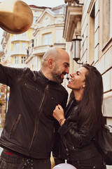 Romantic couple  in casual outfits toasting with champagne  outdoors and  posing on streets of european city. Beautiful woman clinking with her husband.Happy couple with a glass of wine 