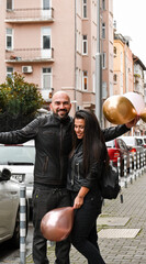Fototapeta na wymiar Romantic couple in casual outfits toasting with champagne outdoors and posing on streets of european city. Beautiful woman clinking with her husband.Happy couple with a glass of wine 