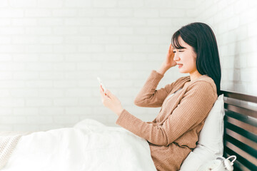 ベッドルームにいる女性（寝る前スマホ・困る）

