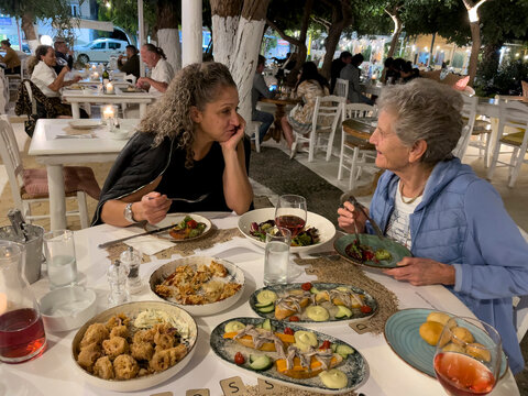 Malia, Crete, Greece. 2022. Two women enjoying a selection of starters during supper in a Greek restaurant.