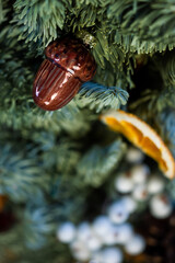A closeup shot of a festive decor element with fir branches and an acorn.