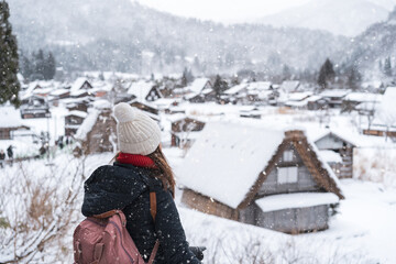 Young woman traveler looking at the beautiful UNESCO heritage village in the snow in winter at...