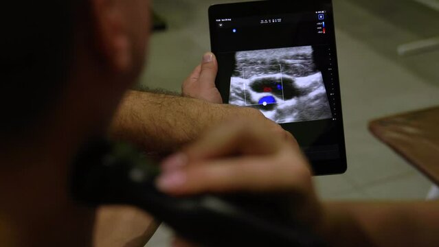 Doctor diagnoses a man in the neck with an ultrasound scanner, makes an X-ray computer procedure. Doppler sonogram of a patient in the surgical department