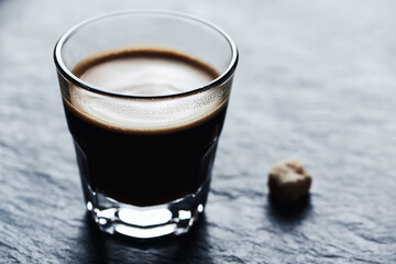 Coffee in glass cup on dark stone background. Close up.	