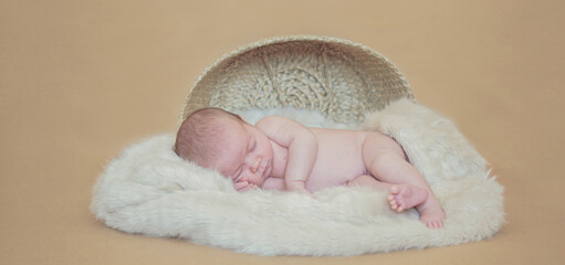 Newborn shooting in aesthetic studio - Cute little baby sleeping pacefuly in a fur out of basket in a beige background