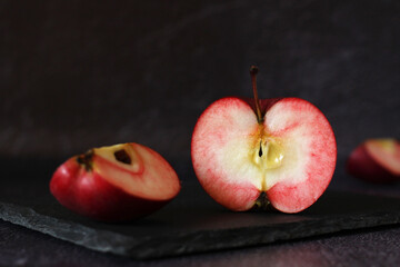 red fresh apple in section and with slices on a dark background