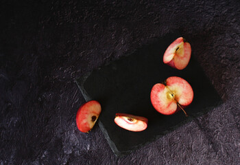 red fresh apple in section and with slices on a dark background