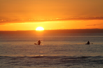 Fototapeta premium Kayakers and paddle boarder enjoy the sunsets on a New Zealand beach