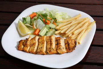 Grilled Chicken Breast with fries, lemon and slice served in a dish isolated on table side view of middle east food