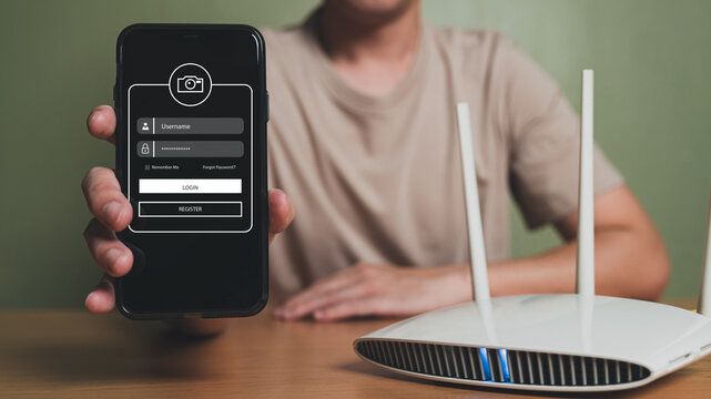 Selective focus at people hand while using smartphone to type password credential to login to Internet wireless connection at home. Network security of internet access into router with futuristic icon