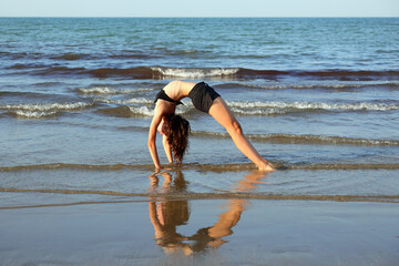 athletic jointed girl who arches her back forms a heart with the reflection on the water