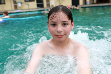 Child doing hydromassage of his chest in thermal pool