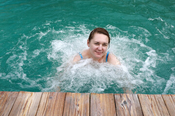 Woman has hydromassage of her chest in thermal pool