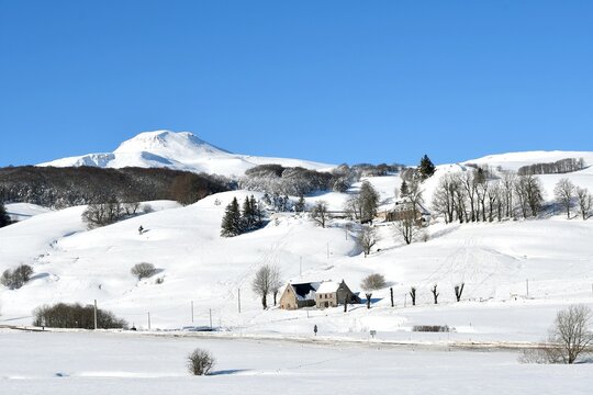 panorama sur le massif du sancy recouvert d'une épaisse couche de neige par une journée ensoleillée avec au loin un buron auvergnat proche de la station de ski de Super Besse dans le puy de dôme