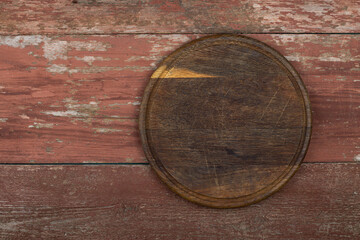 Fototapeta na wymiar Circle cutting board on a red wooden table. Food preparation tool and kitchen utensils.