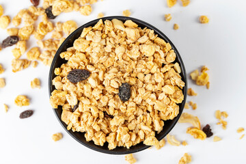 Granola bowl with raisins, nuts. Homemade crunchy granola scattered on white background, top view.