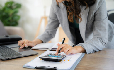Investors working using calculator to calculate with smartphone, laptop the tax of static in...