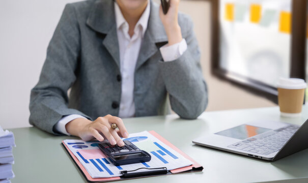 Business Women Or Accountant Working On Laptop Computer With Business Document, Graph Diagram And Calculator On Office Table In Offic