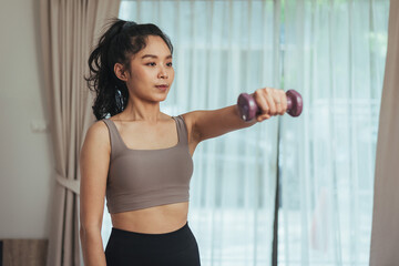 Fototapeta na wymiar Asian woman exercise at home. Healthy female in sportswear workout training with dumbbell in living room, Health care and wellness concept.