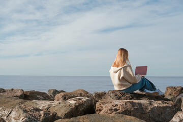 Remote work.Girl freelancer works remotely on the sea shore. workation, remote work,WFVH,Van Life vibes work from vacation home,work travel,remotely work.Travelling.Work from vacation remotely