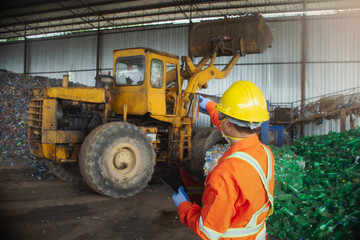 engineer worker in protective uniform and with hardhat using tablet for checking working. recycling industry.