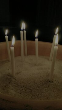 vertical video of candles on a sand ground